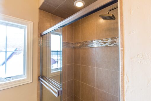 Presidio shower with stone tile and mosaic band