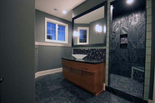 Haven bathroom with wood vanity and dark tile shower