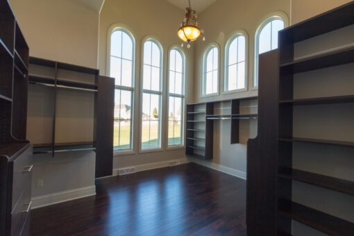 Callista walk-in closet with built-in shelving and arched windows