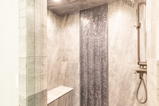 Birchwood walk-in shower with herringbone tile accent and bench