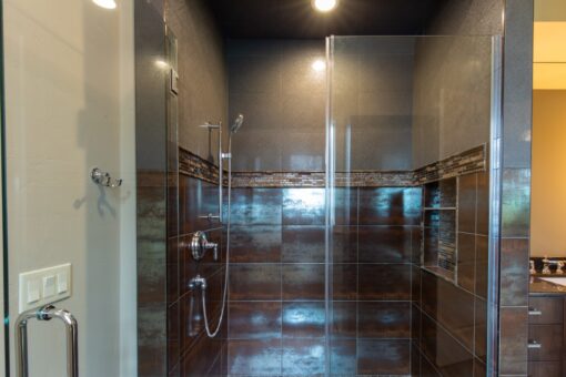 Grand Haven walk-in shower with dark tile and glass