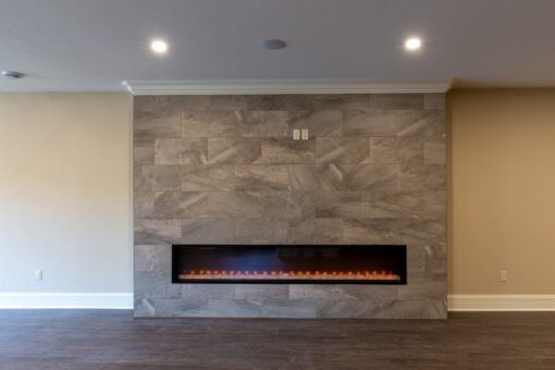 Rivendell lower-level linear fireplace with stone wall