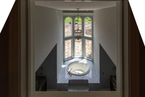 Grand Haven soaking tub under an arched window and chandelier