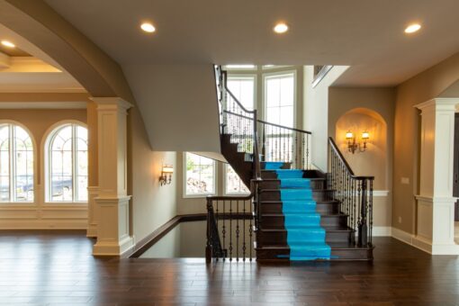 Grand Haven foyer staircase with iron balusters and tall windows