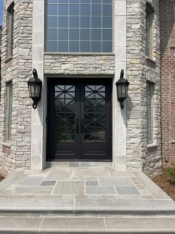 Birchwood iron and glass double entry doors with stone surround