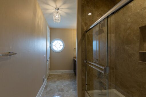 Stone Creek bathroom with glass shower and round window