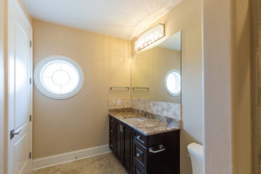 Stone Creek bathroom with round window and dark vanity