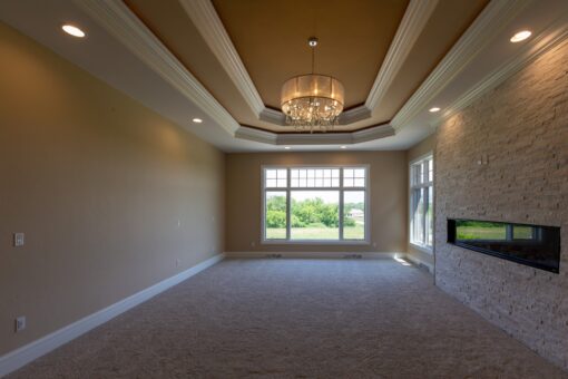 Stone Creek primary bedroom with tray ceiling and chandelier