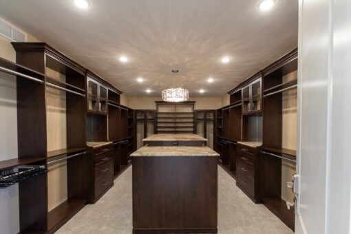 Stone Creek primary closet with dark wood cabinetry and island