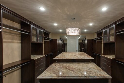 Stone Creek primary closet with granite island and chandelier