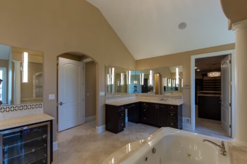 Stone Creek primary bath with dark vanities and arched doorway