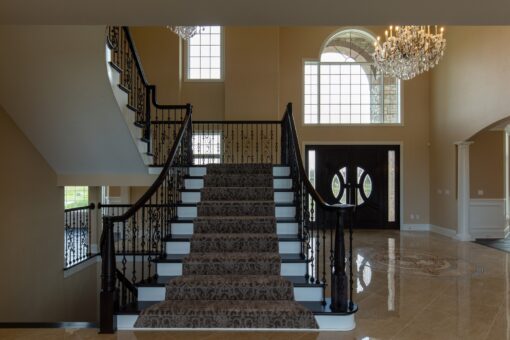 Stone Creek foyer staircase with carpet runner and iron railing