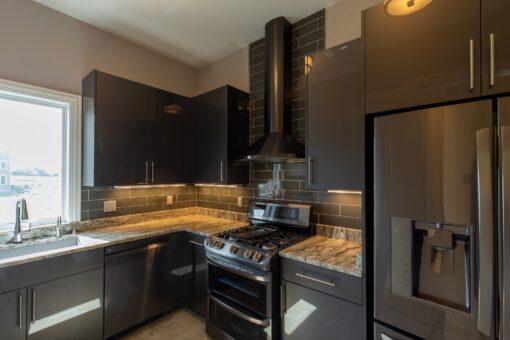 Stone Creek kitchen with dark cabinetry, range hood and stainless appliances