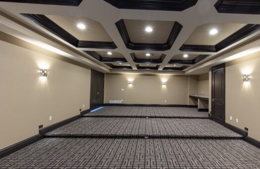 Stone Creek lower-level home theater with coffered ceiling and patterned carpet
