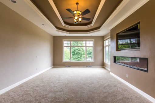 Kingfogl custom home bedroom with tray ceiling and linear fireplace