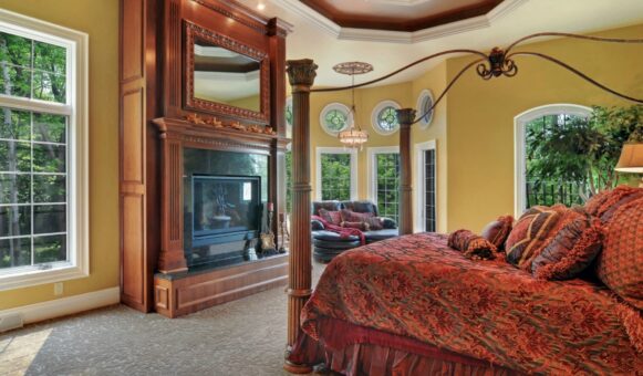 Kingfogl custom home primary bedroom with carved fireplace mantel and canopy bed