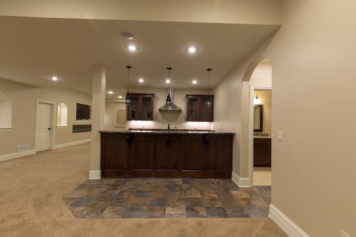 Kingfogl custom home lower-level bar with dark cabinetry and slate floor inset