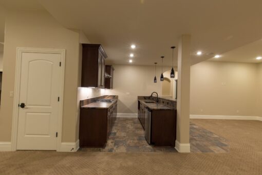 Kingfogl custom home lower-level bar with dark cabinetry and tile floor