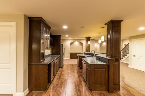 Kingfogl custom home lower-level bar with dark wood cabinetry and columns
