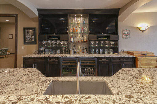 Bradon lower-level bar with dark cabinetry and granite