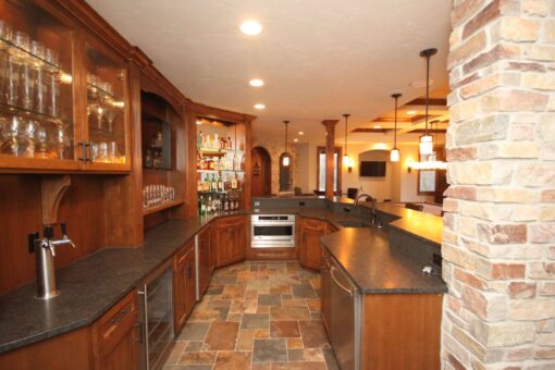 Kingfogl custom home wet bar with glass-front cabinets, beer tap and stone column
