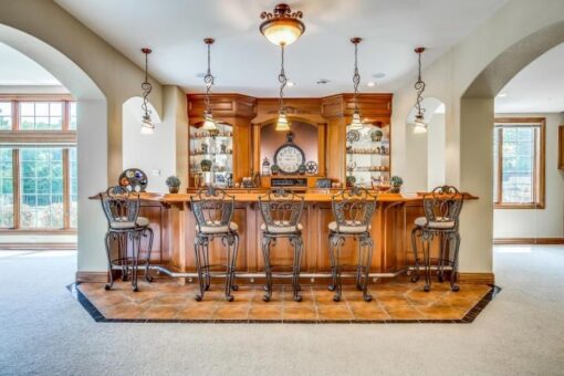 Kingfogl custom home lower-level bar with arched openings, wood bar and stools