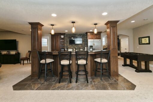 Kingfogl custom home lower-level bar with wood columns, stools and game area