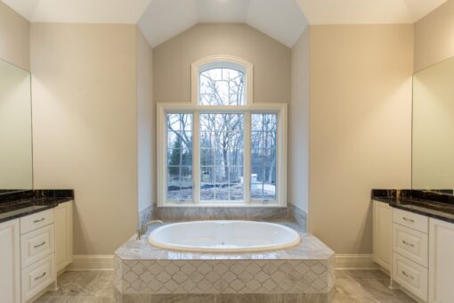 Woodview primary bath soaking tub beneath an arched window
