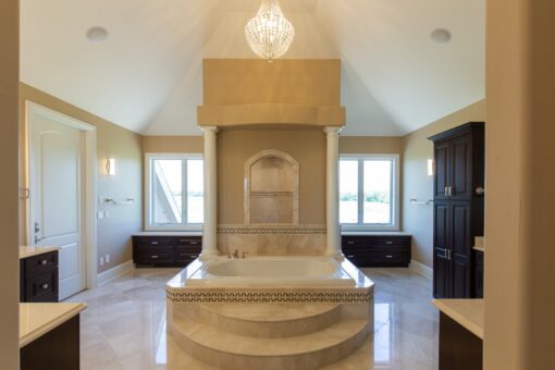 Stone Creek primary bath tub in a columned alcove with chandelier