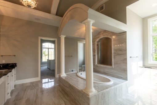 Kingfogl custom home primary bath with columned tub alcove and dark granite vanity