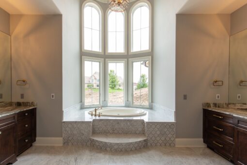 Grand Haven primary bath soaking tub beneath arched windows