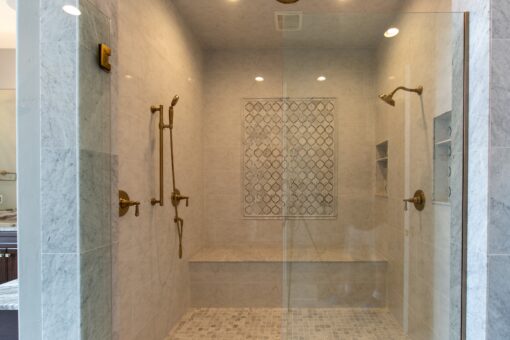 Kingfogl custom home glass walk-in shower with brass fixtures and mosaic accent panel