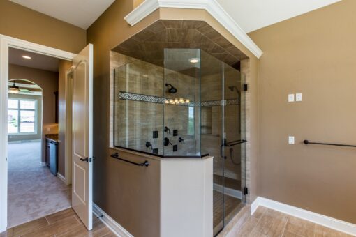 Kingfogl custom home corner glass shower with dark tile and arched surround