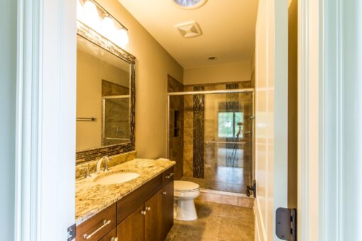 Kingfogl custom home bathroom with wood vanity and tiled shower beyond