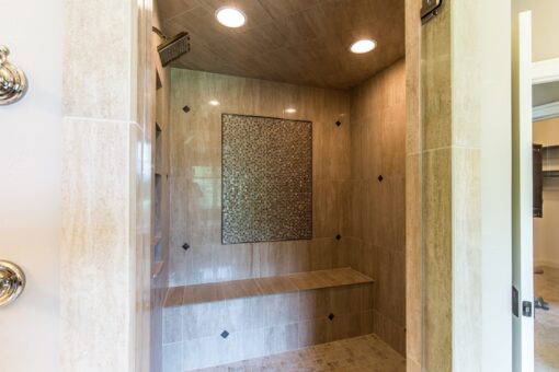 Kingfogl custom home walk-in travertine shower with mosaic panel and bench