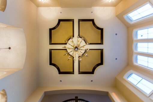 Kingfogl custom home ceiling with gold inlay panels and chandelier beside arched windows