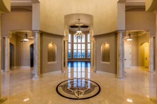 Kingfogl custom home foyer with marble medallion floor, columns and arched niches