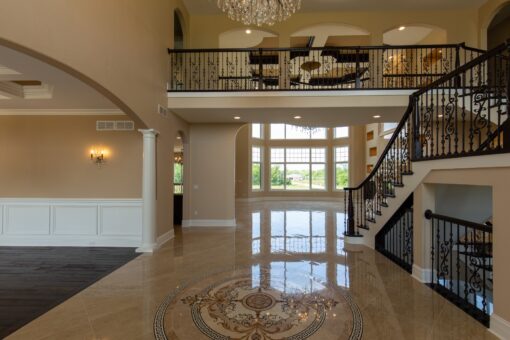 Kingfogl custom home foyer with marble medallion, iron staircase and balcony