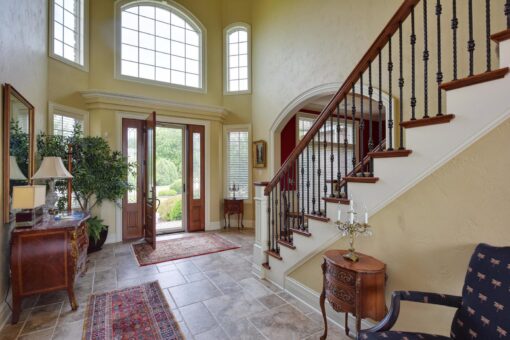 Kingfogl custom home foyer with wood staircase and arched entry doors