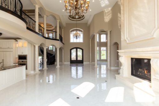 Kingfogl custom home foyer with curved iron balcony, fireplace and arched entry doors