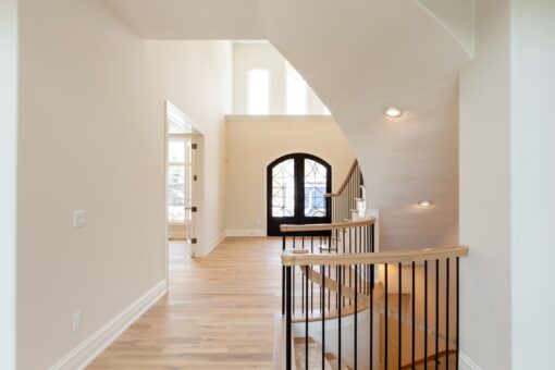Kingfogl custom home foyer with arched entry door and open staircase railing