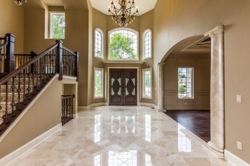 Kingfogl custom home foyer with iron staircase, arched entry doors and chandelier
