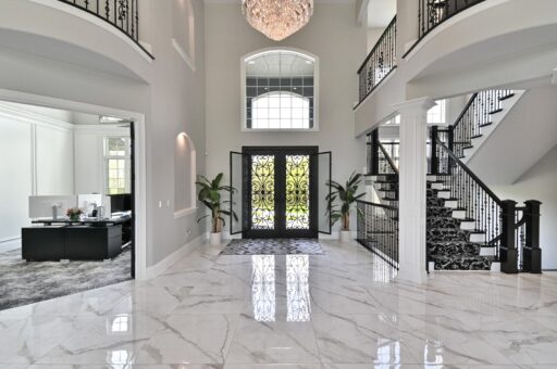 Woodland foyer with arched iron entry doors and chandelier
