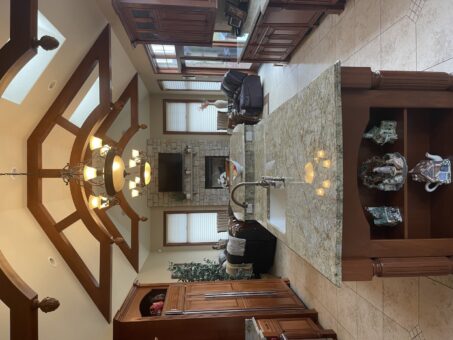 Kingfogl custom home hearth room with timber trusses and stone fireplace beyond the kitchen island