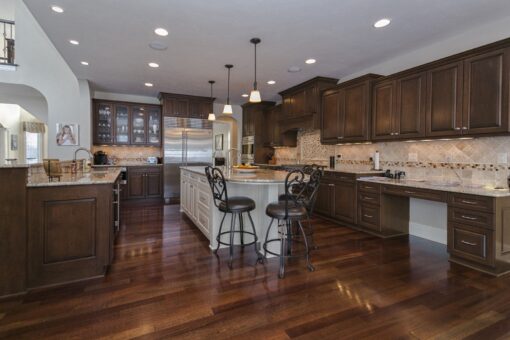 Kingfogl custom home kitchen with dark wood cabinetry and white island with stools