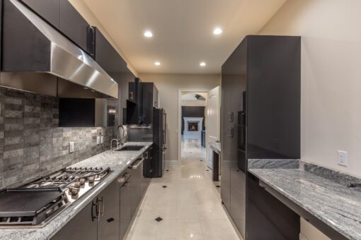 Kingfogl custom home galley prep kitchen with gray cabinetry and stainless hood