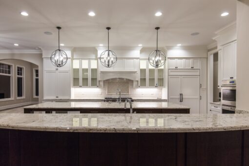 Kingfogl custom home white kitchen with curved granite island and globe pendants