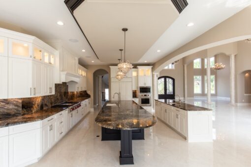 Kingfogl custom home white kitchen with oval granite island and arched windows