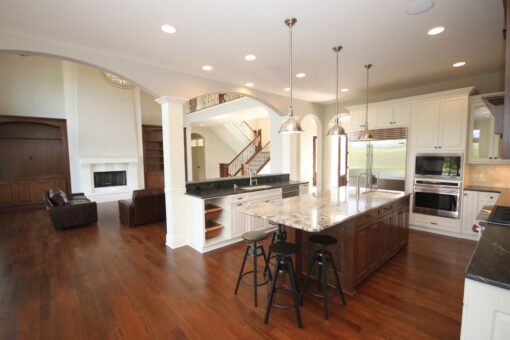 Kingfogl custom home kitchen with white cabinetry, wood island and view to the great room