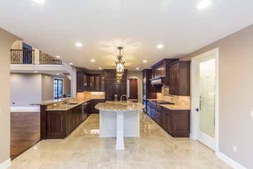 Kingfogl custom home kitchen with dark wood cabinetry, island and arched doorway